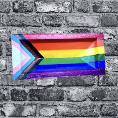 The inclusive pride flag is painted on to a brick, against a backdrop of black and white bricks. The purpose is to reflect that the therapists provides LGBTQ+ affirming and friendly counselling and psychotherapy